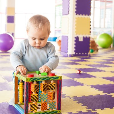 Boy plays with cube One year's old toddler boy plays with fine motor skills cube at the playroom
